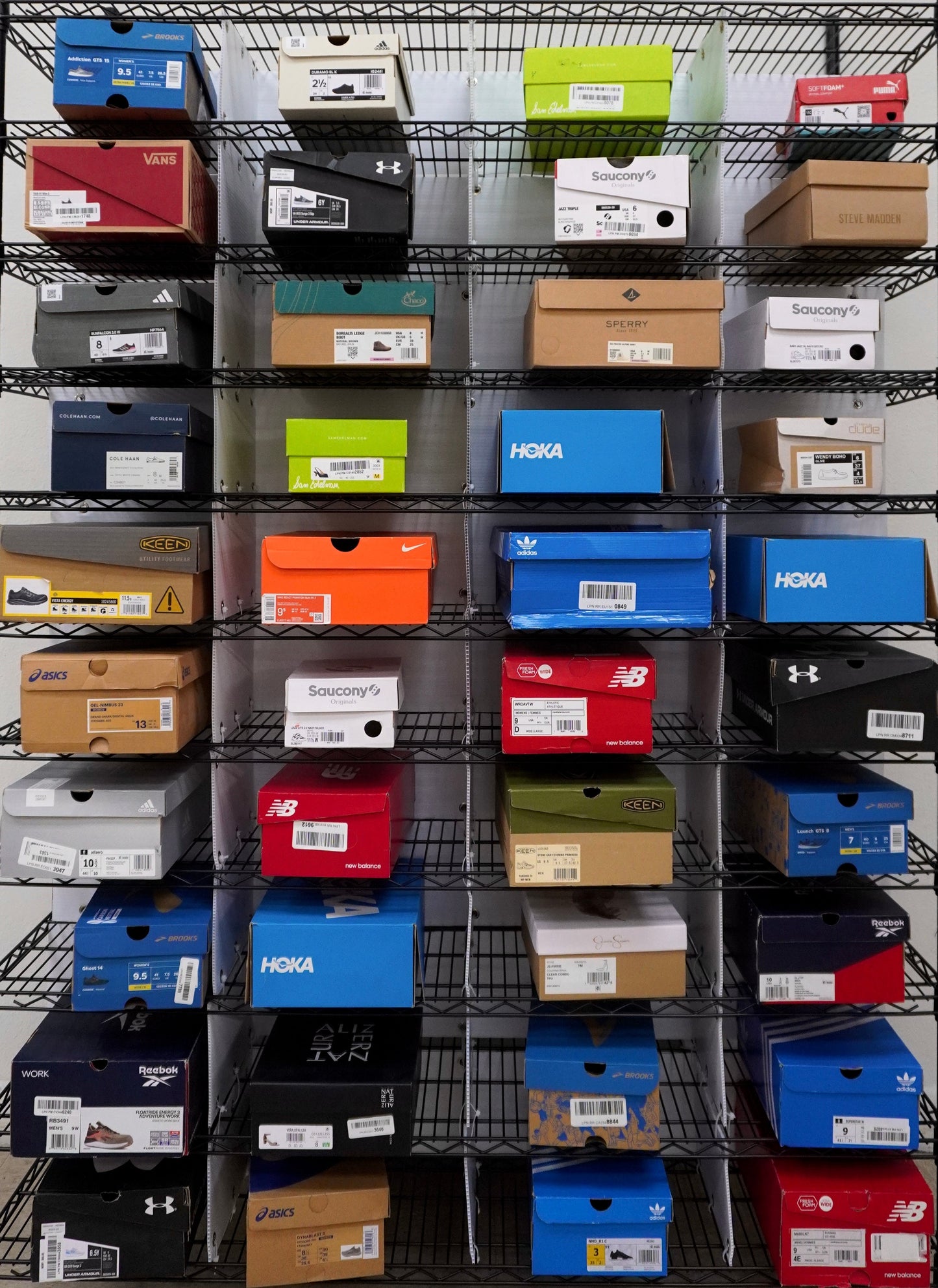 Metal shoe rack with various colored boxes on a white wall background