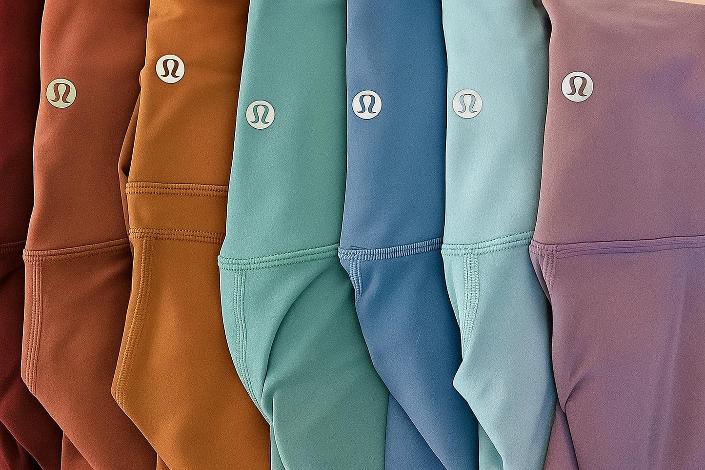 Row of colorful shorts with a brand logo on each, displayed in a gradient from brown to purple.